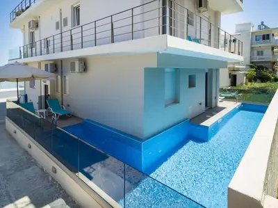 a house with a swimming pool and a balcony at Sonja Beachfront Apartments in Kato Daratso