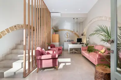 a living room with pink chairs and a staircase at Viaggio Elegant Rooms in Chania Town