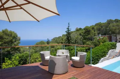 a deck with chairs and an umbrella next to a pool at VILLA TERRA CRETA Luxury Retreat and Spa in Chania Town
