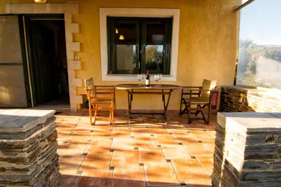 a patio with a table and chairs and a window at Villas Paleochora in Palaiochóra