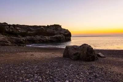 a rocky beach with a rock on the shore at Villas Paleochora in Palaiochóra