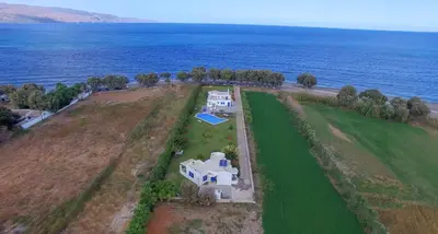 an aerial view of a house on a field next to the ocean at Oasea in Tavronitis