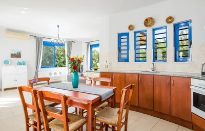a kitchen with a table and chairs and a kitchen with blue windows at Oasea in Tavronitis