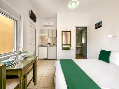 a bedroom with a bed and a desk and a kitchen at Akti Galinis in Kalyves