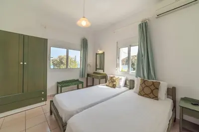 a bedroom with two beds and two windows at Akti Galinis in Kalyves