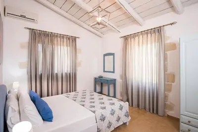 a bedroom with a white bed with blue pillows at Kontis Village in Fílippos