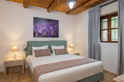 a bedroom with a bed with two tables and two windows at Kontis Village in Fílippos