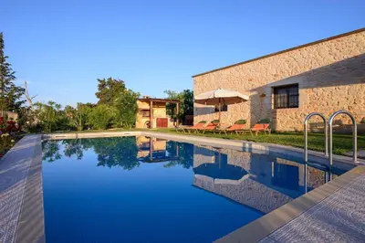 a swimming pool in front of a building with a house at Kontis Village in Fílippos