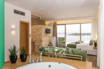 a bathroom with a bed and a living room with a tub at Kalamaki Luxury Suites in Kalamaki Chanion