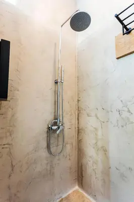 a shower in a bathroom with a stone wall at Kalamaki Luxury Suites in Kalamaki Chanion