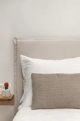 a white bed with a white pillow and a night stand at Kamares Sanctuaries in Kolymvari