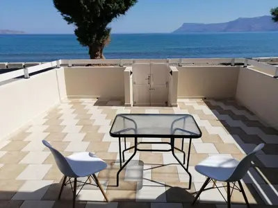 a patio with a table and two chairs and the ocean at Beach House in Kissamos