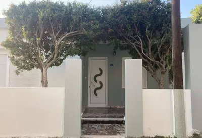 a white house with a door with trees in front at Cityscape House in Chania Town