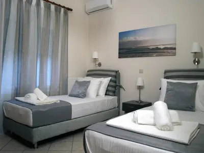 a hotel room with two beds and a chair at Urban Sea Apts in Chania Town