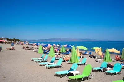 a group of chairs and umbrellas on a beach at Anna Katerina Apartments in Plataniás