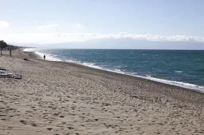 a beach with a person walking on the sand at Anna Katerina Apartments in Plataniás