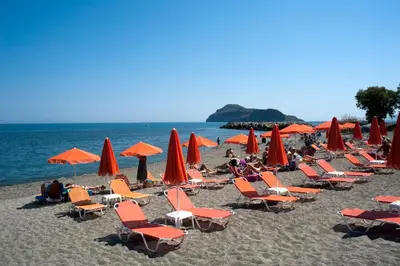 a group of chairs and umbrellas on a beach at Anna Katerina Apartments in Plataniás