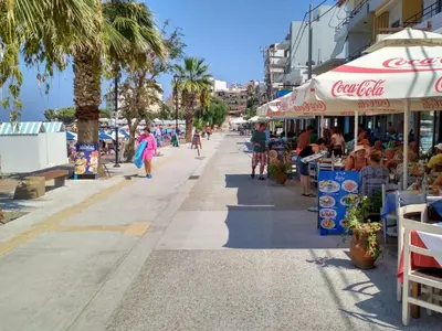 a street with people walking on a beach with palm trees at UTOPIA luxury apartment in Chania Town