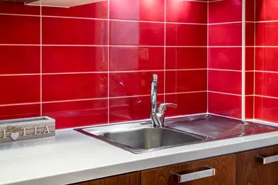 a kitchen sink with a red tiled wall at Sevach Apartments in Kalamaki Chanion