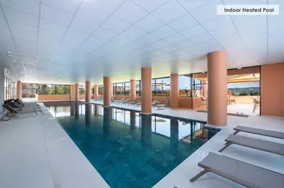 a swimming pool in a building with tables and chairs at Kiani Beach Resort Family All Inclusive in Kalyves