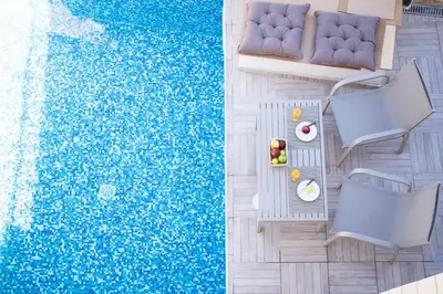 an overhead view of a swimming pool with chairs and a table at Villa Sirocos in Stalos