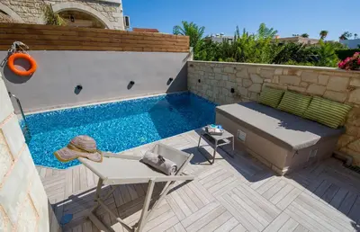 a patio with a pool and a chair and a table at Villa Sirocos in Stalos