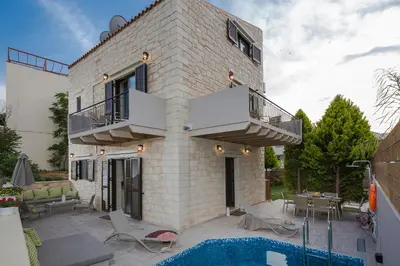 a brick house with a balcony and a swimming pool at Villa Sirocos in Stalos