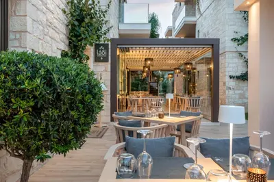 a restaurant with tables and chairs in front of a building at Airis Boutique Hotel & Suites - For adults only in Kato Daratso