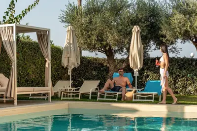 a man and a woman standing next to a swimming pool at Airis Boutique Hotel & Suites - For adults only in Kato Daratso