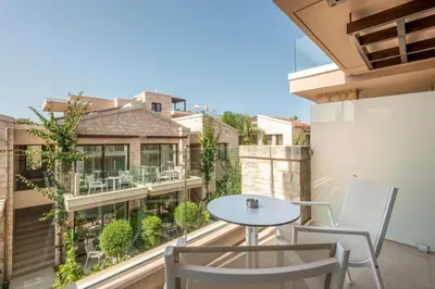 a patio with a table and chairs on a balcony at Airis Boutique Hotel & Suites - For adults only in Kato Daratso