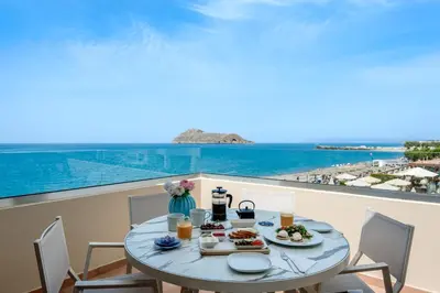 a table with food on a balcony with a view of the ocean at Blue Dome Hotel in Plataniás