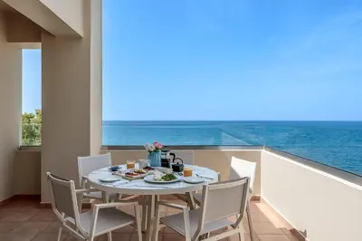 a dining room with a table and chairs and the ocean at Blue Dome Hotel in Plataniás