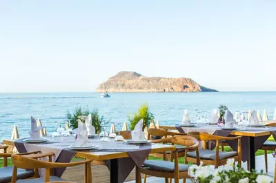 a table set up for a meal with the ocean in the background at Blue Dome Hotel in Plataniás