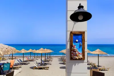 a beach with chairs and umbrellas and the ocean at Ariadne Beach in Plataniás