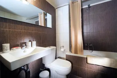 a bathroom with a sink and a toilet and a mirror at Rafalia Cozy Apartment in Chania Town