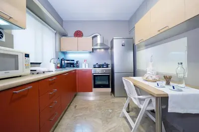 a kitchen with red cabinets and a table and a refrigerator at Rafalia Cozy Apartment in Chania Town