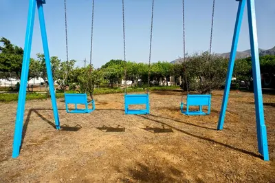 four blue chairs sitting on a swing set at Dolphin Apartments in Frangokastello