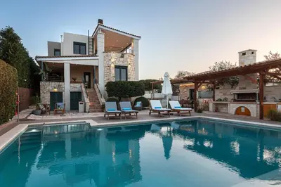 a swimming pool with two chairs and a house at Antonia Blue Villa in Mourniaí