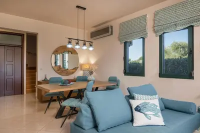 a dining room with a blue couch and a table at Antonia Blue Villa in Mourniaí