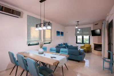 a living room with a table and blue chairs at Antonia Blue Villa in Mourniaí