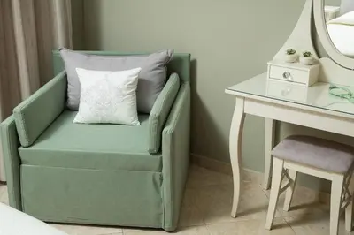 a green chair with a pillow next to a desk at Villa Ira in Chorafakia