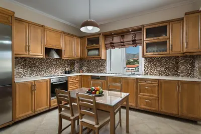 a kitchen with wooden cabinets and a table with a bowl of fruit at Villa Ira in Chorafakia