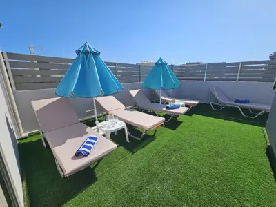 a patio with chairs and umbrellas on a balcony at Elegant 2BR Apartment in Chania Town
