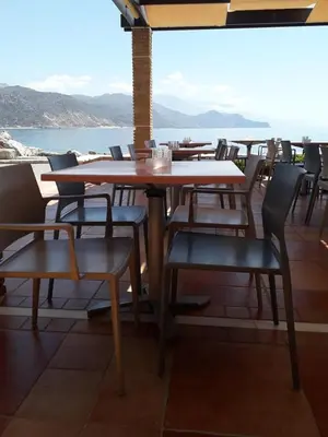 a table and chairs on a balcony with a view of the ocean at On The Rocks in Palaiochóra