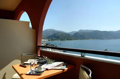 a balcony with a table with a view of the water at On The Rocks in Palaiochóra