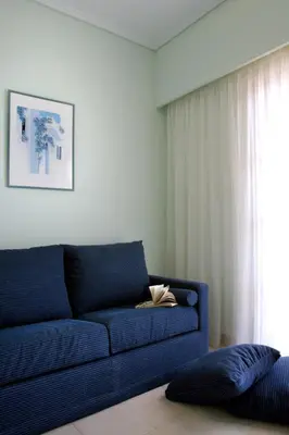 a blue couch in a living room with a window at On The Rocks in Palaiochóra