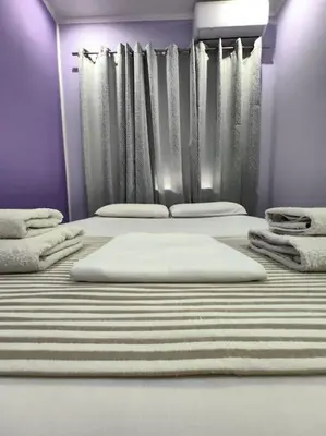 three beds in a room with a purple wall at Nina Apartment in Chania Town