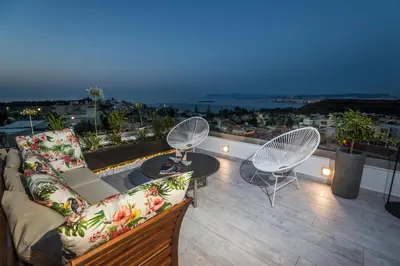 a balcony with a couch and chairs on a roof at The Hill House Villa in Kato Daratso