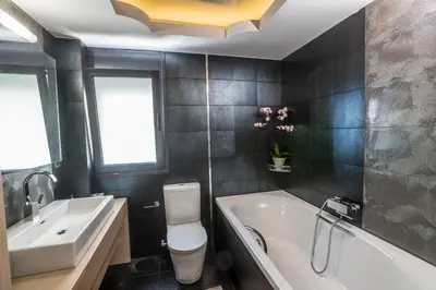 a bathroom with a tub and a toilet and a sink at The Hill House Villa in Kato Daratso