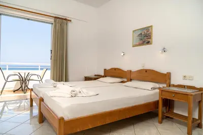 a bedroom with two beds and a balcony at Hotel Mimoza in Agia Marina Nea Kydonias